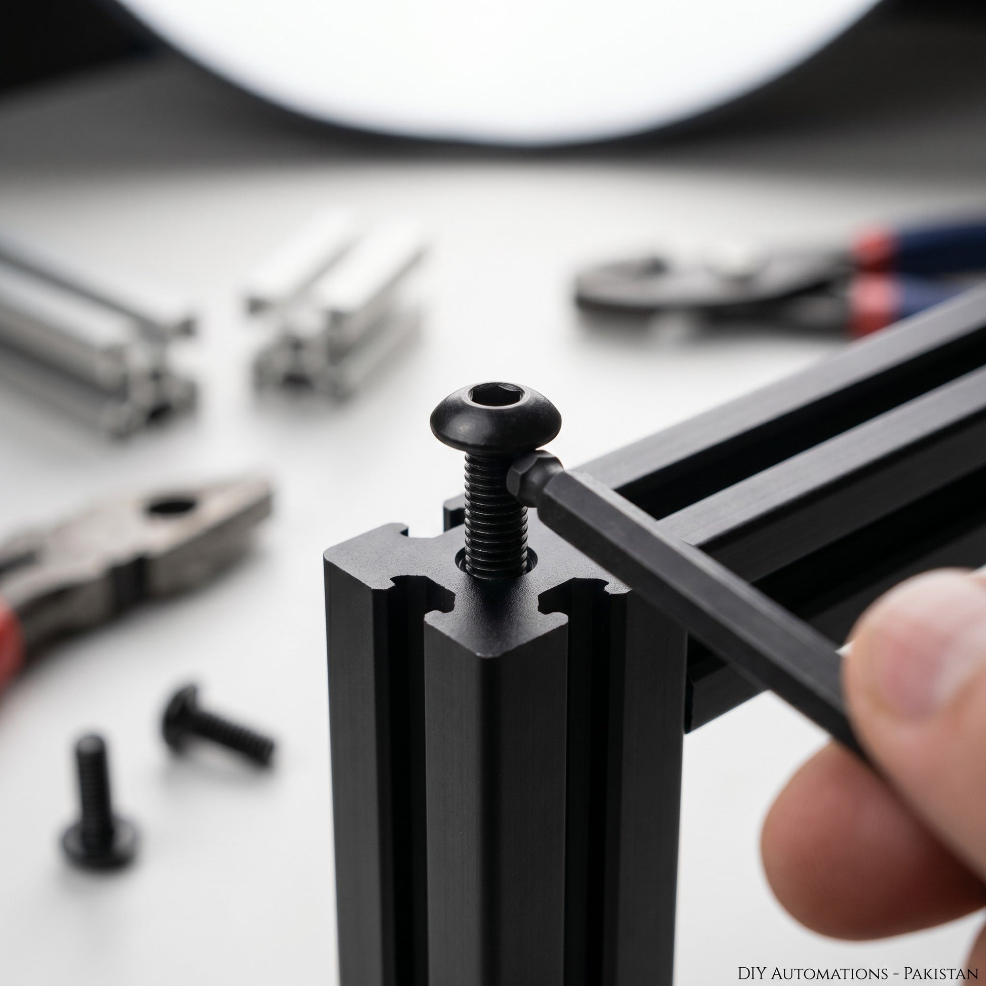 DIY AUTOMATIONS M5x12 black alloy steel button head socket cap screw being tightened into aluminum extrusion profile